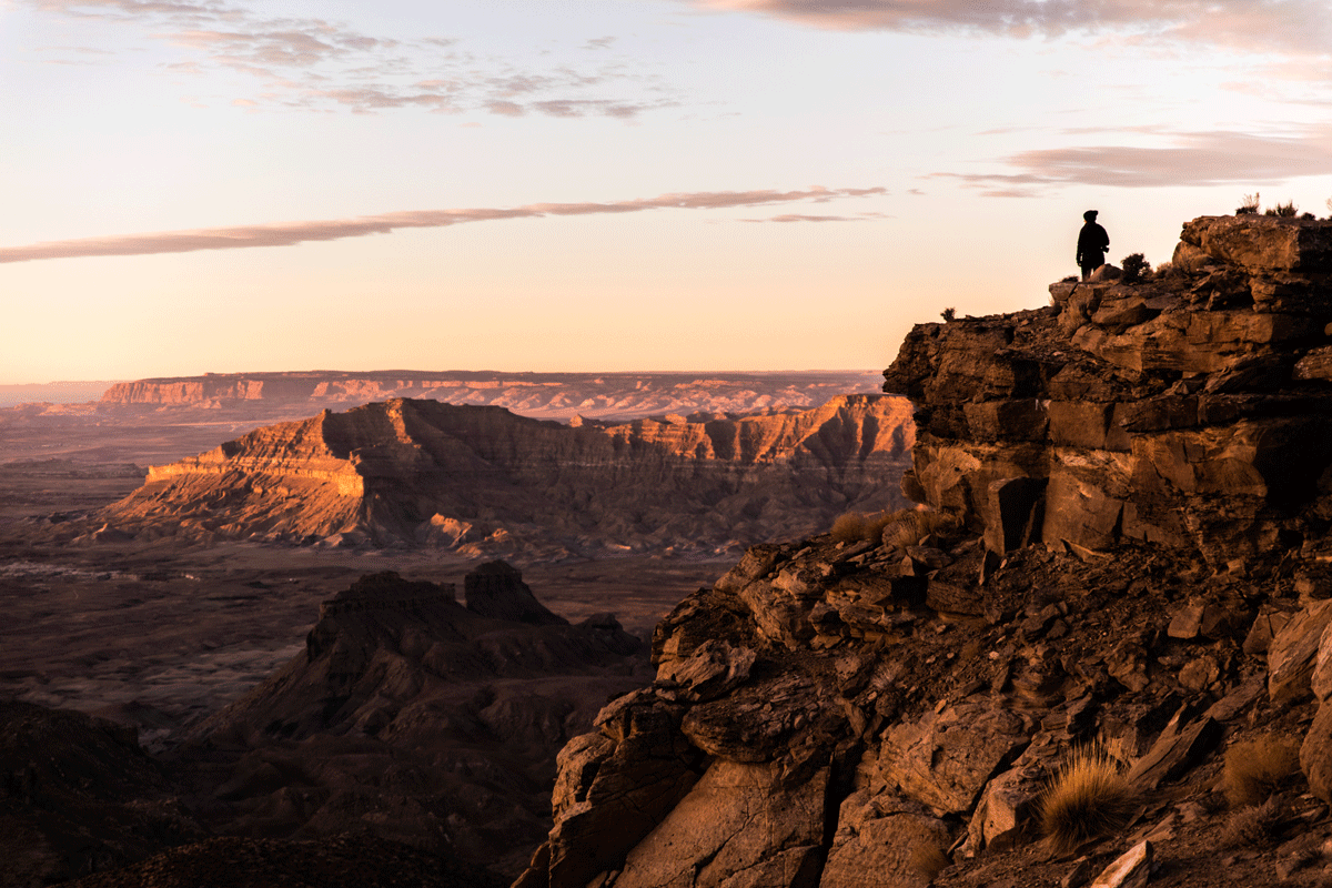 Hiker looking down into canyons during sunset